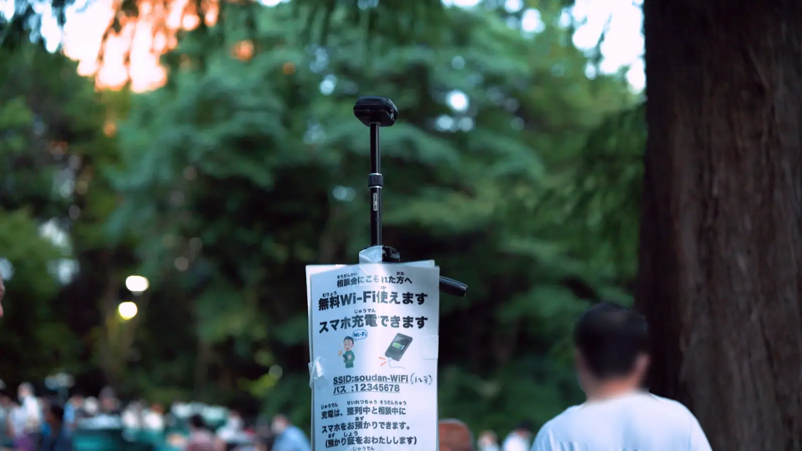 夜の公園で開かれる相談会。無料Wi-Fiとスマホ充電の案内が掲げられている