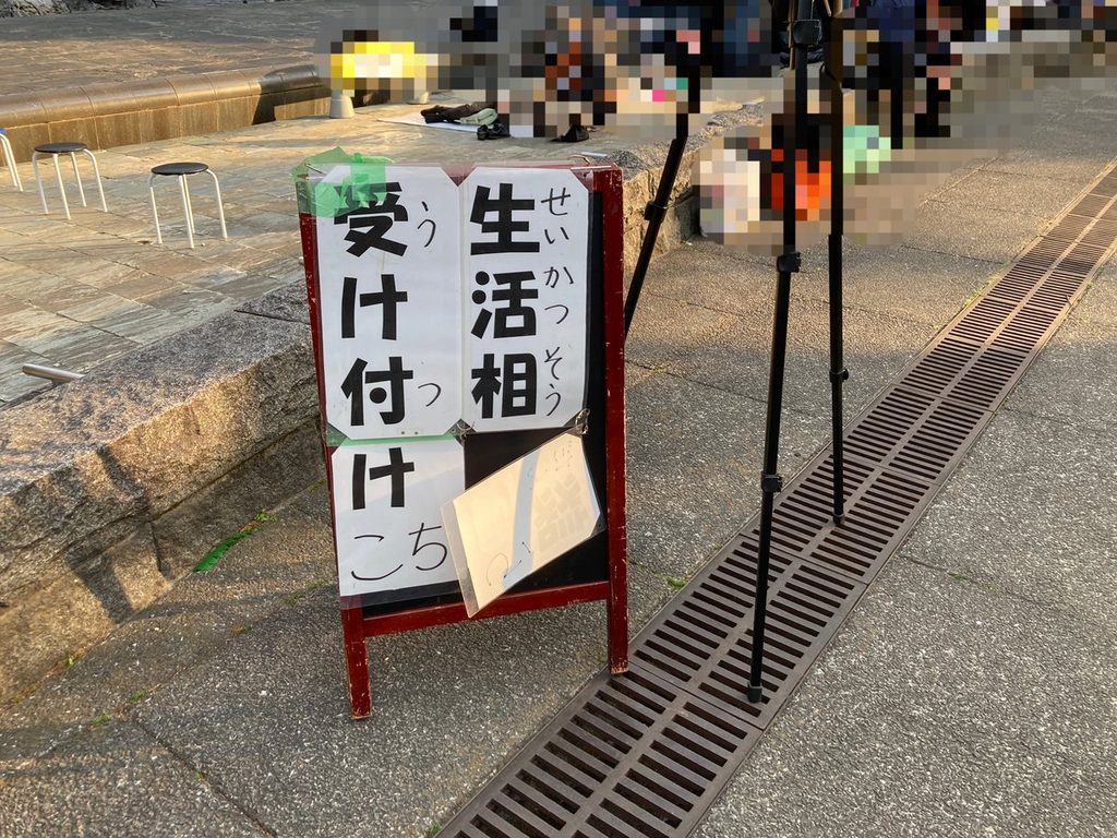 「生活相談 受け付けこちら」と書かれた、会場入口のA型看板