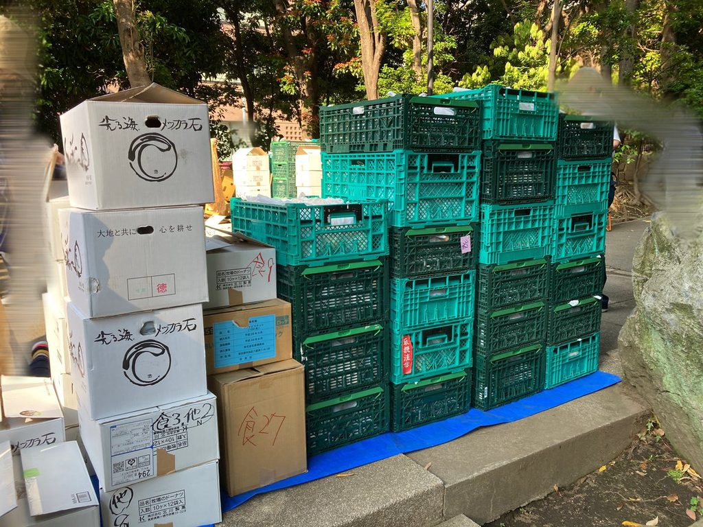 会場に積み上げられた、配布用の食料が入ったコンテナと段ボール箱