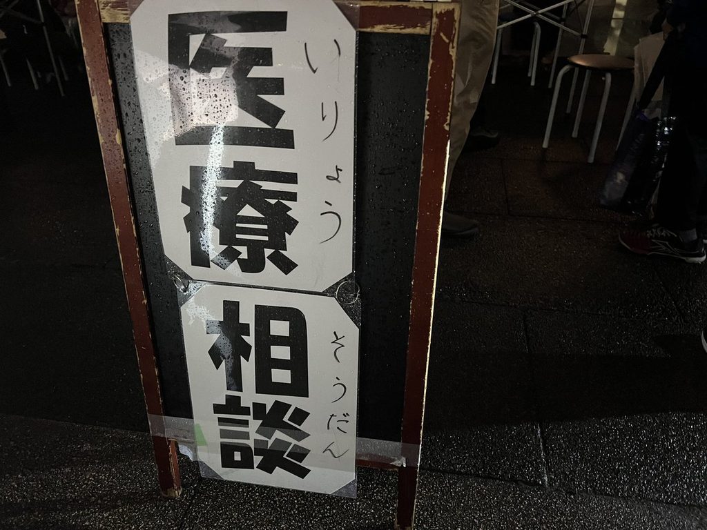 夜の会場に立てられた「医療相談」の立て看板