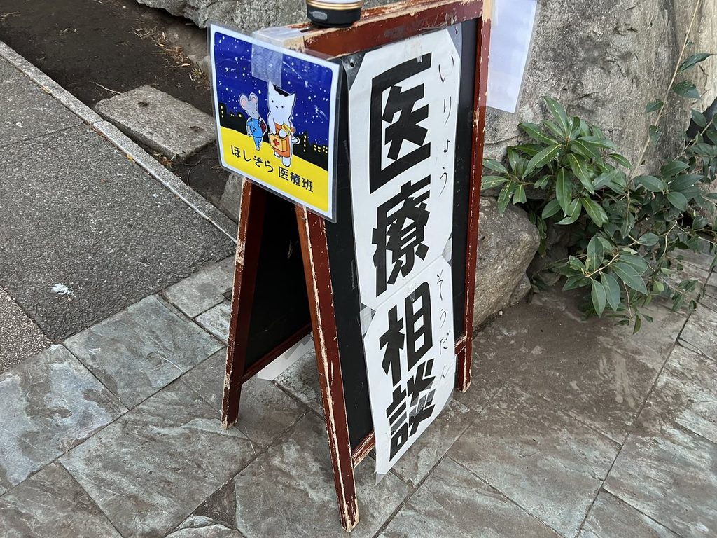「医療相談」と書かれたA型看板。ほしぞら医療班のイラストが添えられている