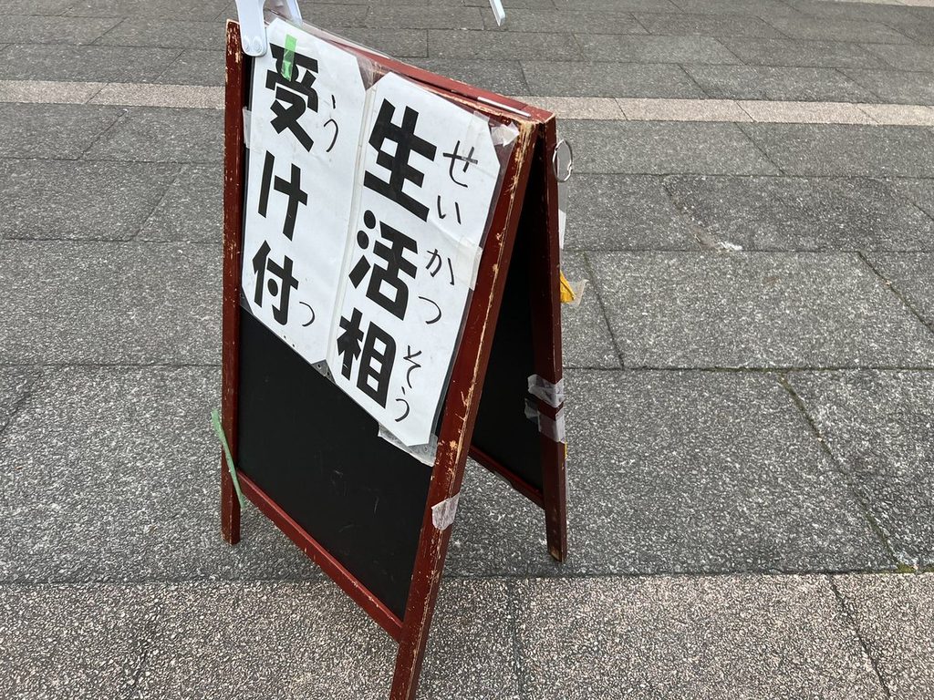 「生活相談 受け付け」のA型看板と、その隣に置かれた黒板