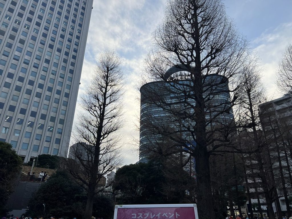 コスプレイベントの案内が立つ会場と、東池袋の木立