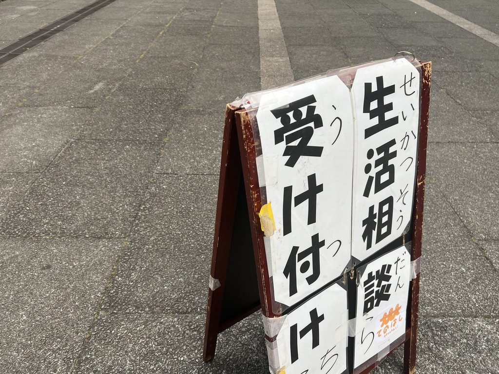 晴れた日の会場に立つ「生活相談 受け付け」のA型看板