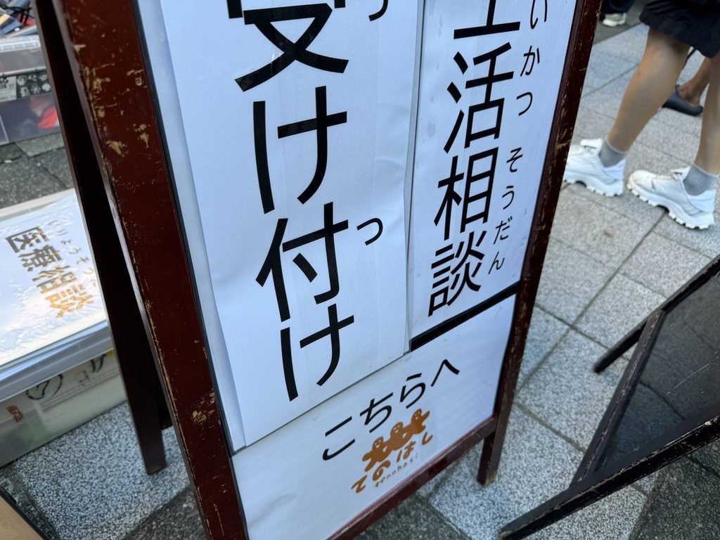 「生活相談 受け付けこちらへ」のA型看板