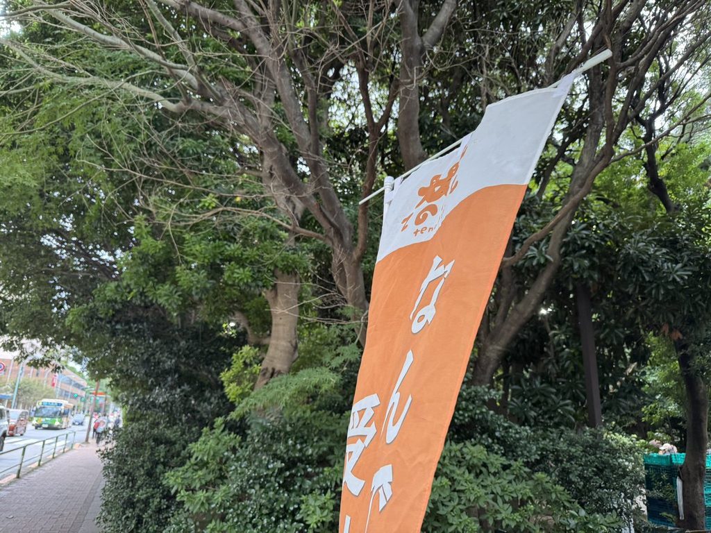 木立の下に立てられた「なんでも相談」のオレンジ色ののぼり