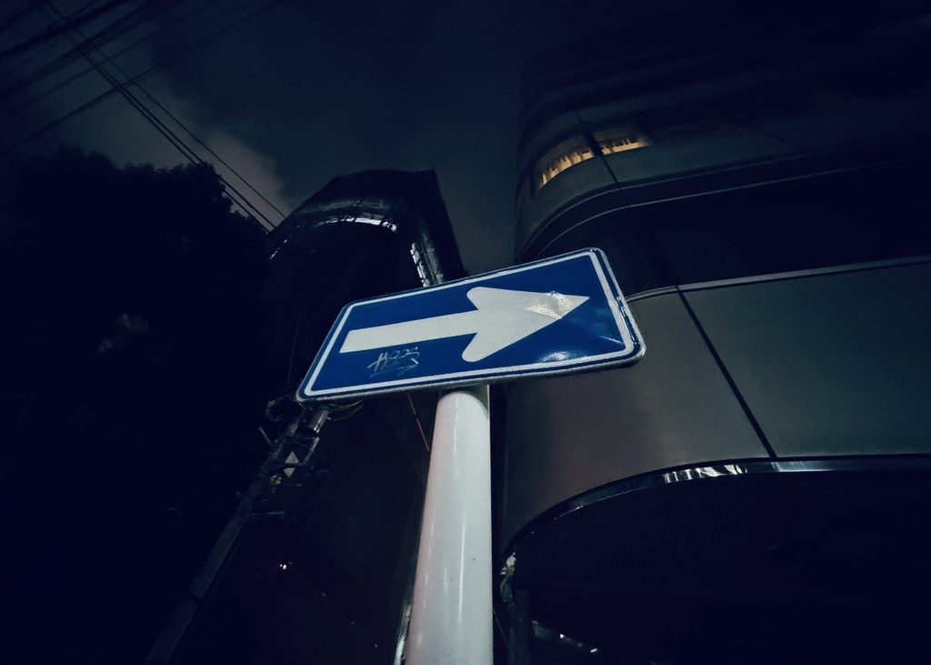 夜の街角。青い矢印の道路標識
