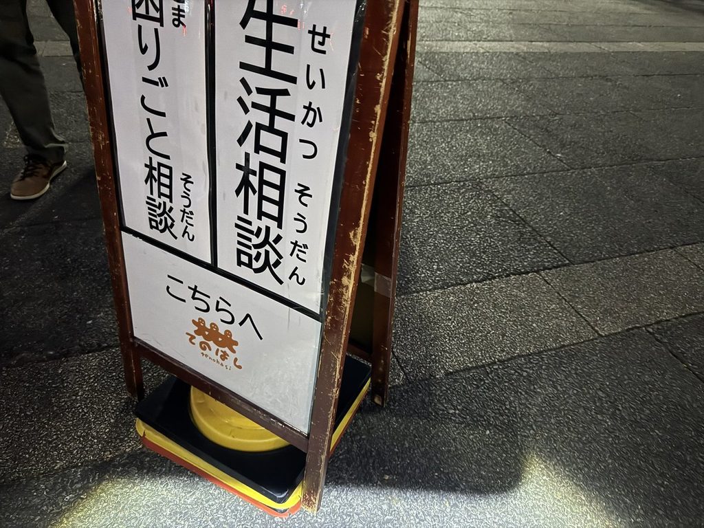 大みそかの会場に立つ「生活相談 困りごと相談 こちらへ」のA型看板