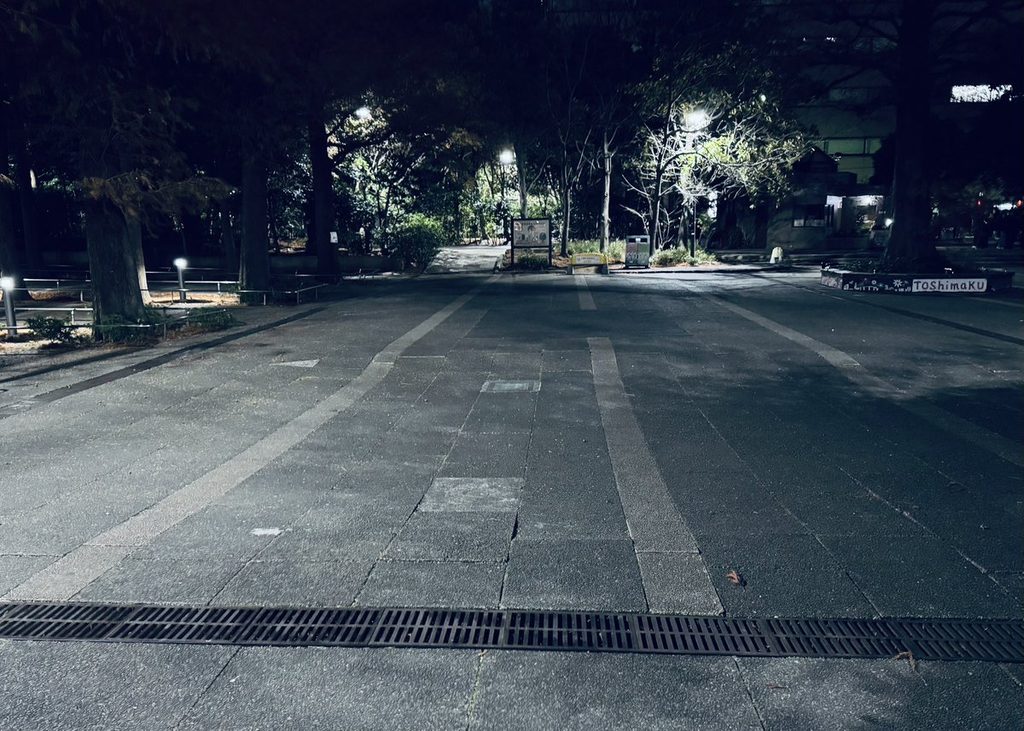 夜の公園。街灯に照らされた広場