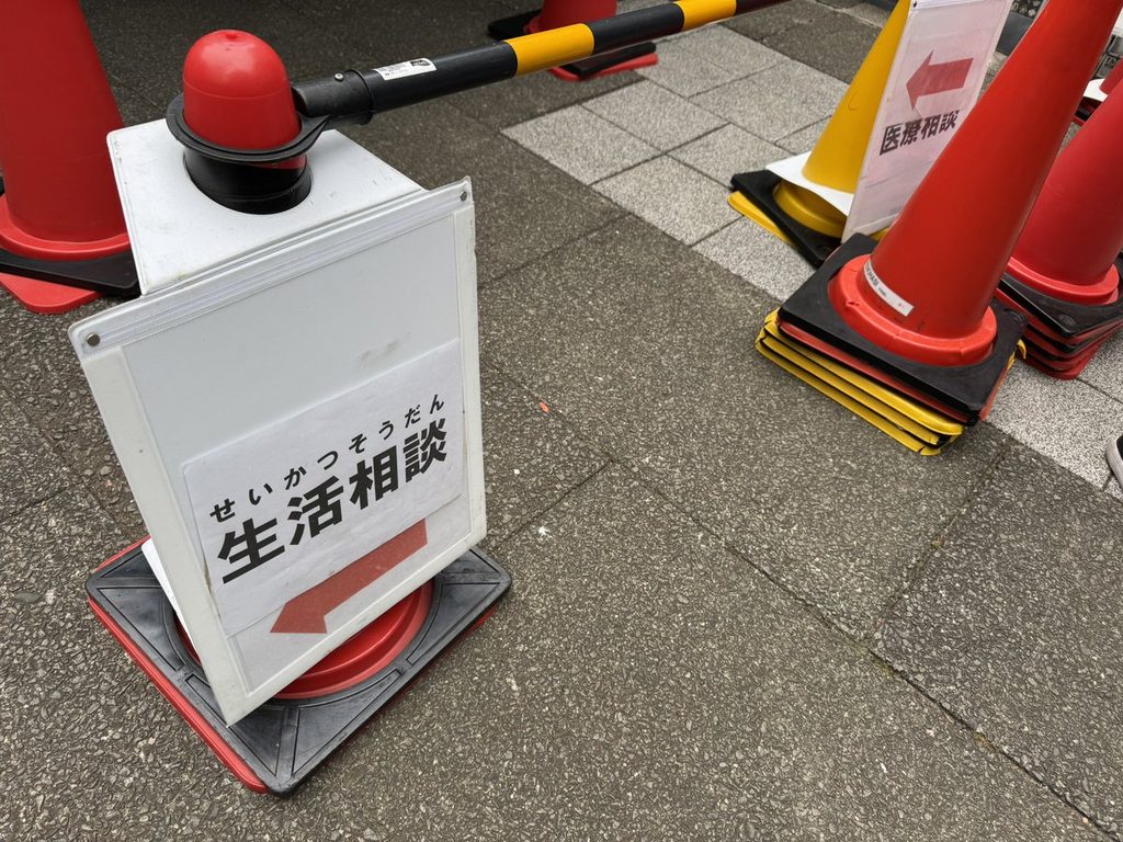 「生活相談」の矢印つき案内板と、赤いカラーコーン