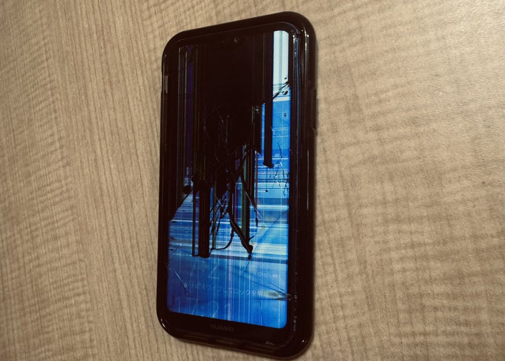 机の上に置かれた、画面の割れたスマートフォン