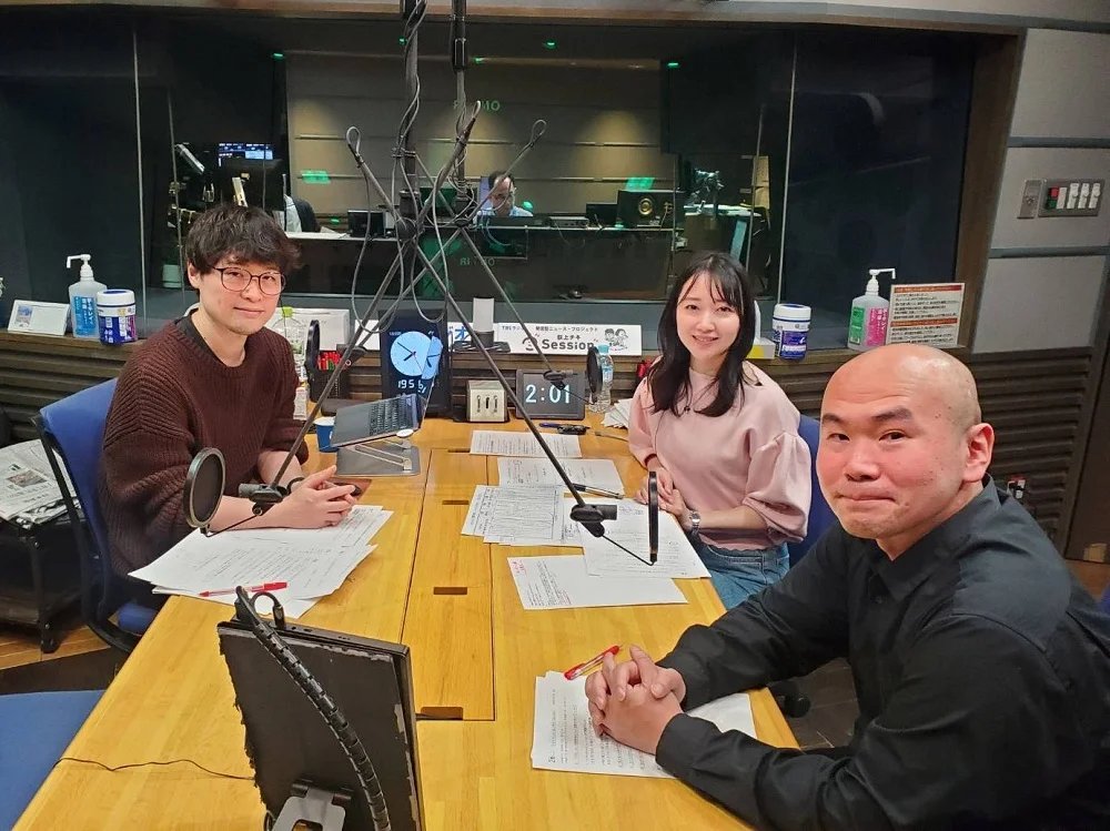 TBSラジオのスタジオ。マイクの並ぶテーブルを囲んで、番組の出演者が着席している