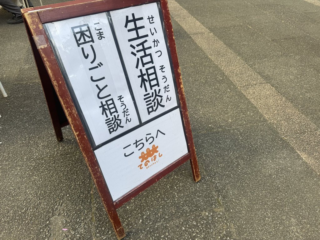 「生活相談 困りごと相談 こちらへ」と書かれた、てのはしのA型看板